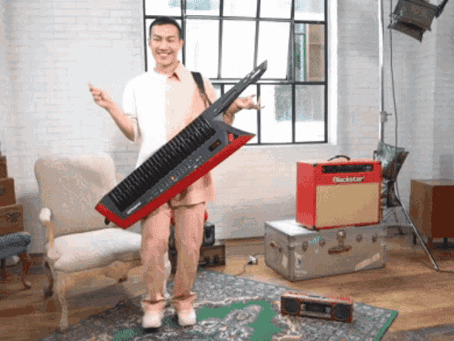 a man is holding a large keyboard in front of a red blackstar amplifier
