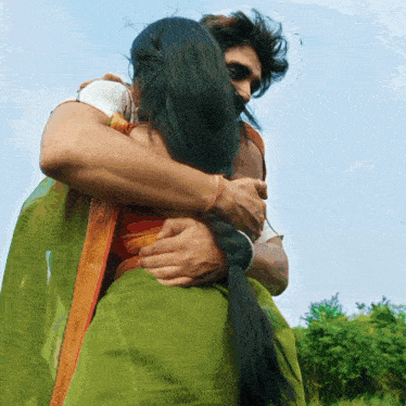 a man is hugging a woman who is wearing a green dress