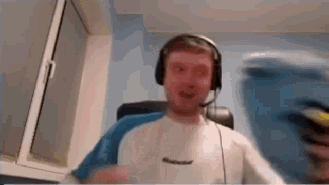 a man wearing headphones and a headset is sitting in front of a window .