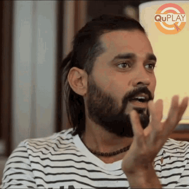 a man with a beard is wearing a striped shirt and has the word quplay on the bottom right