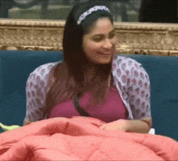 a woman is sitting on a blue couch with a pink blanket