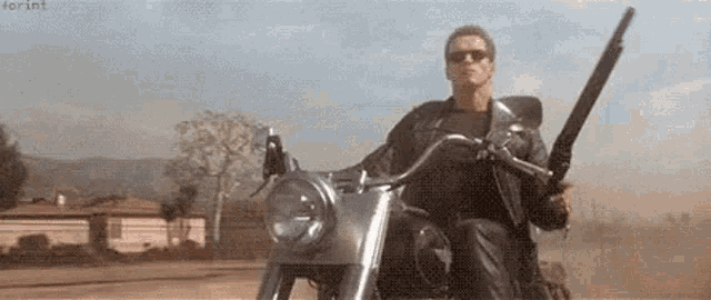 a man is riding a motorcycle with a gun on his shoulder .