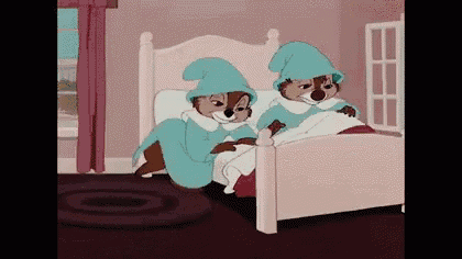 two cartoon squirrels are sitting on a bed wearing blue robes .