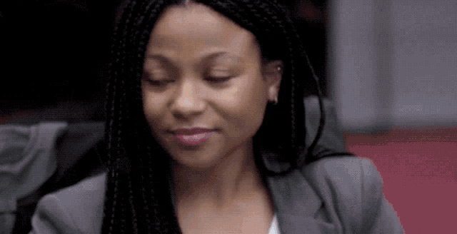 a close up of a woman with braids wearing a gray jacket