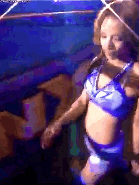 a woman in a blue top and shorts is standing in a dark room .
