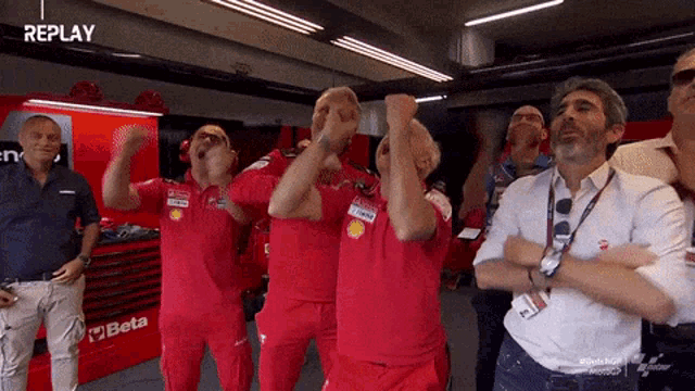 a group of men are standing in a room with the word replay on the bottom right
