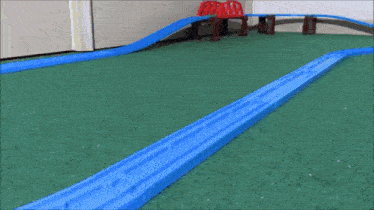 a toy train is going down a track with a red bridge in the background