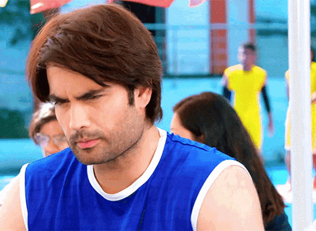 a man wearing a blue tank top is looking down
