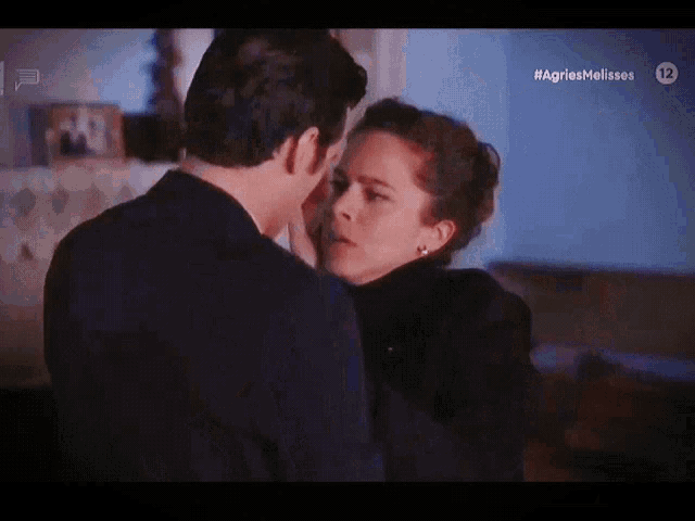 a man and a woman are kissing in front of a sign that says #agnesmelisses