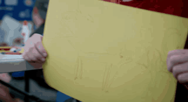 a person is holding a yellow piece of paper with a drawing of a horse on it