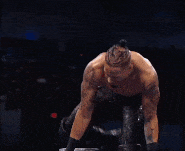 a wrestler is jumping over the ropes in front of a crowd