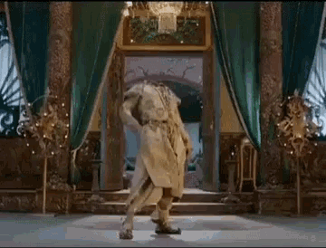 a man in a white dress is dancing in a room with a green curtain .