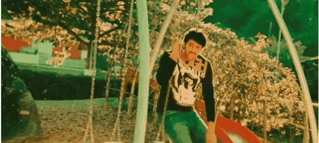 a man is sitting on a swing wearing a shirt that says ' death '
