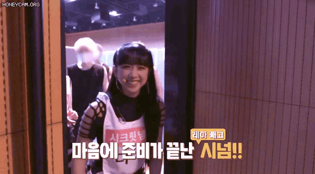 a girl in a white tank top is smiling in a doorway