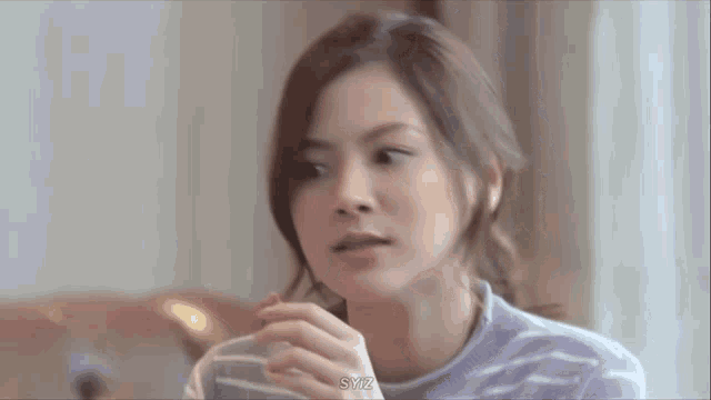 a woman in a striped shirt is holding a cup of coffee .