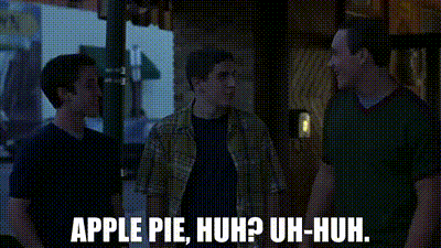 three men are standing next to each other on a sidewalk and one of them is talking about apple pie .