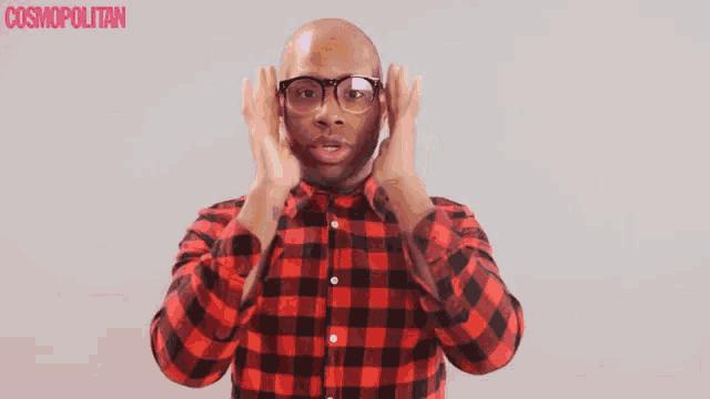 a man wearing glasses and a plaid shirt is making a funny face