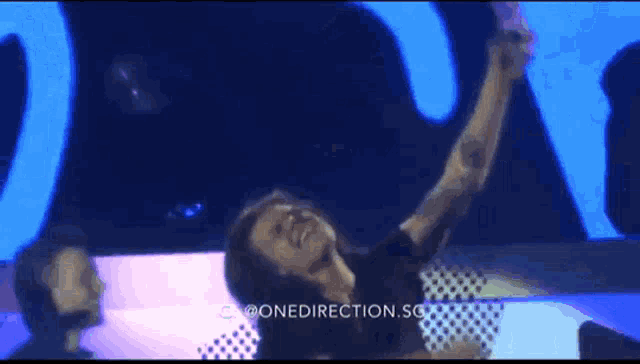 a man taking a picture of himself on a stage with the words one direction sg on the bottom