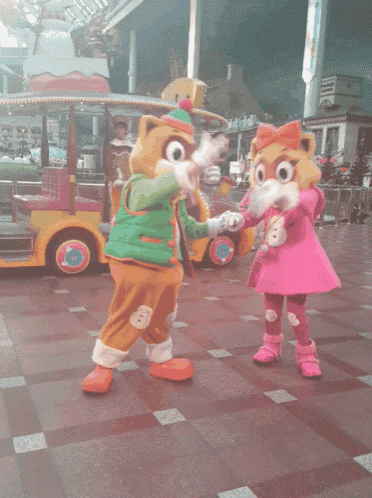 a couple of mascots standing next to each other in front of a vehicle