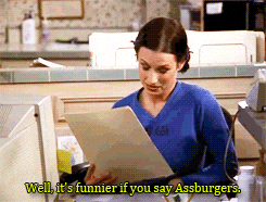 a woman is sitting at a desk holding a piece of paper and says well it 's funnier if you say assburgers
