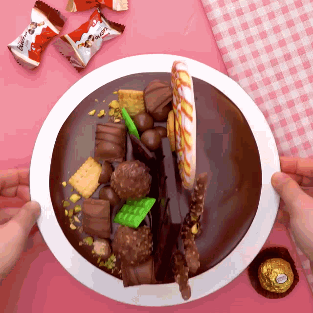 a white plate topped with a chocolate cake and candy including kinder buenos and ferrero rocher