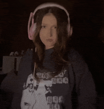 a woman wearing headphones is making a peace sign with her hands .