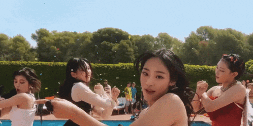 a group of women are dancing around a pool