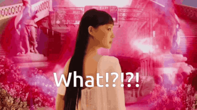 a woman with long hair is standing in front of a pink background with the words what ! ? ! ? written on it .