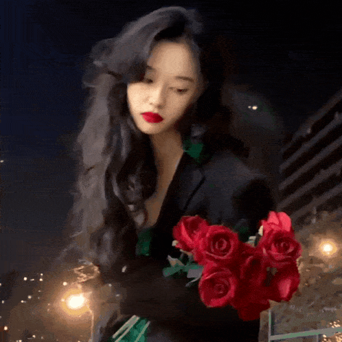 a woman in a black jacket is holding a bouquet of red roses .