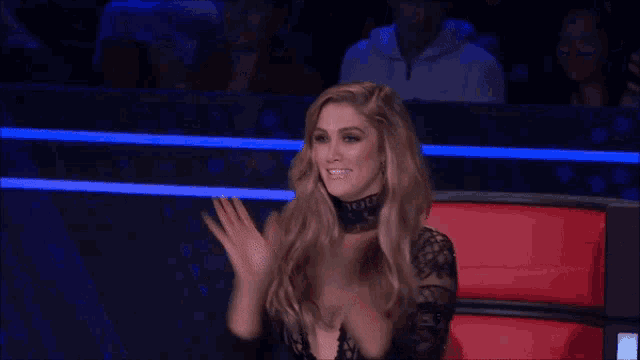 a woman is sitting in a chair with her hands up and smiling