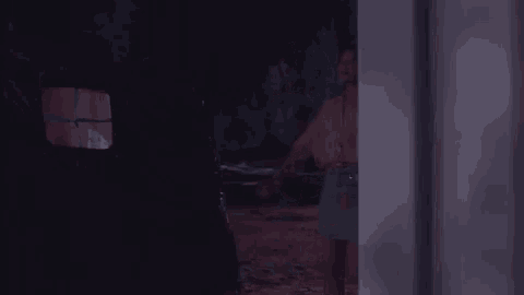 a woman is standing in a doorway at night looking out a window .
