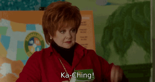 a woman in a red jacket is holding a piece of paper and says ka-ching