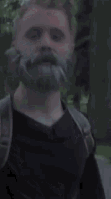 a man with a beard wearing a black shirt and a backpack