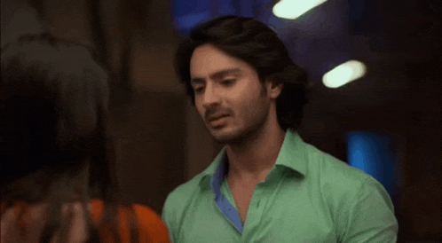 a man in a green shirt is standing next to a woman .