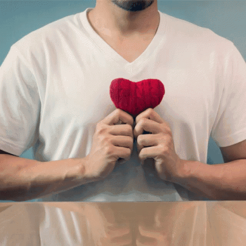 a man in a white shirt is holding a red heart