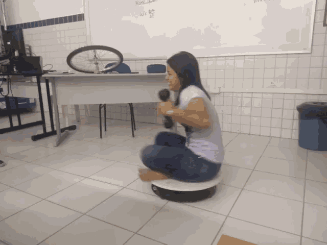 a woman sits on a circular platform holding a microphone