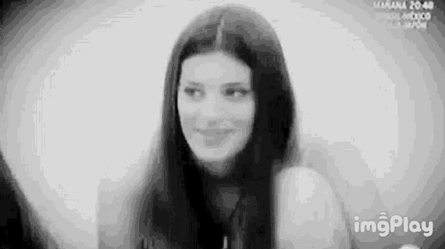 a black and white photo of a smiling woman with long hair .
