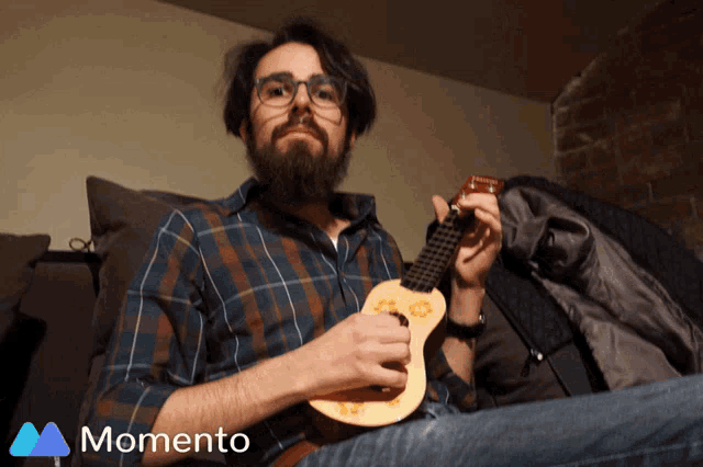 a man with a beard is playing an ukulele in front of an ad for momento