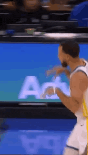 a basketball player is dancing in front of a large screen .