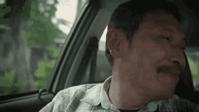 a man is sitting in the back seat of a car with his mouth open .