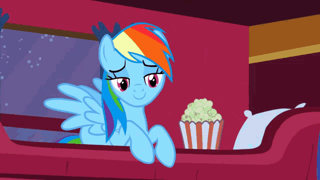 rainbow dash from my little pony sits on a couch with a popcorn bucket