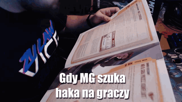 a man is reading a book with the words gdy mg szuka hakka na graczy on it