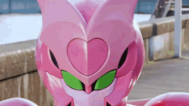 a close up of a pink robot with green eyes and a heart on its head .