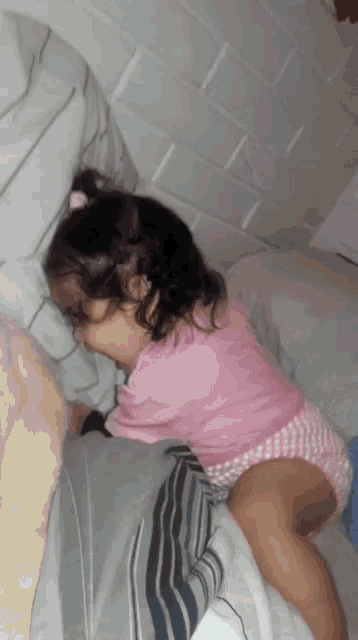 a little girl is sleeping on a bed with her head on a pillow