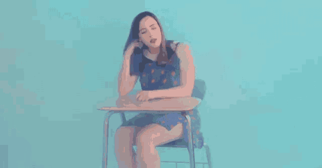 a woman in a blue dress is sitting at a desk .