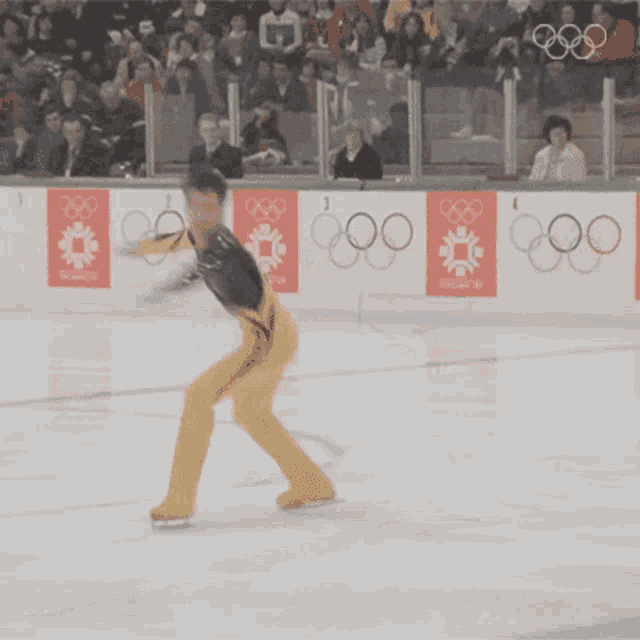 a man is ice skating in front of a wall that says olympics on it