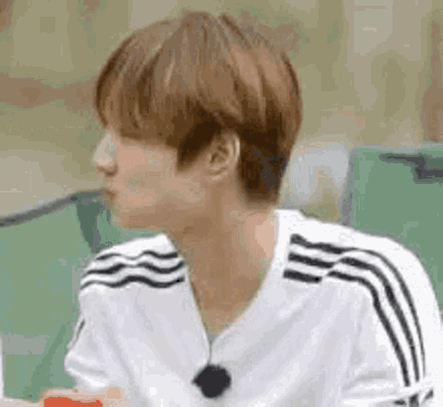 a young man in a white shirt is sitting in front of a tent eating a watermelon .