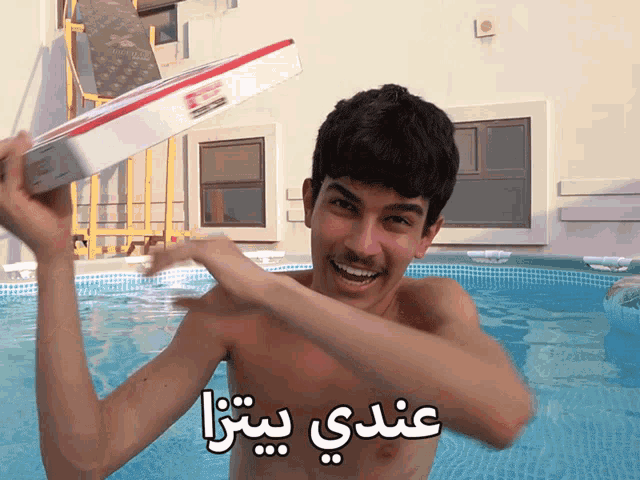 a shirtless man in a swimming pool holding a pizza box