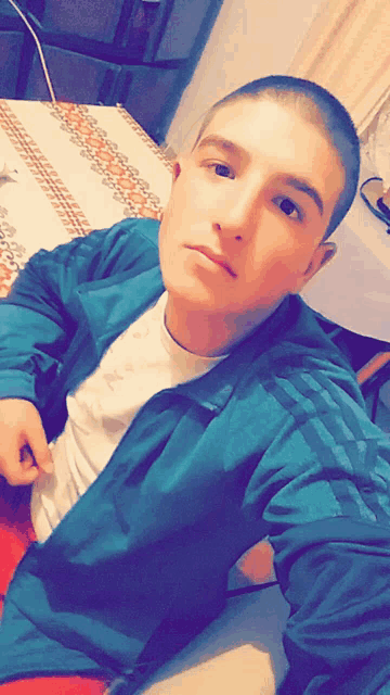 a young man taking a selfie in front of a table with a patterned cloth