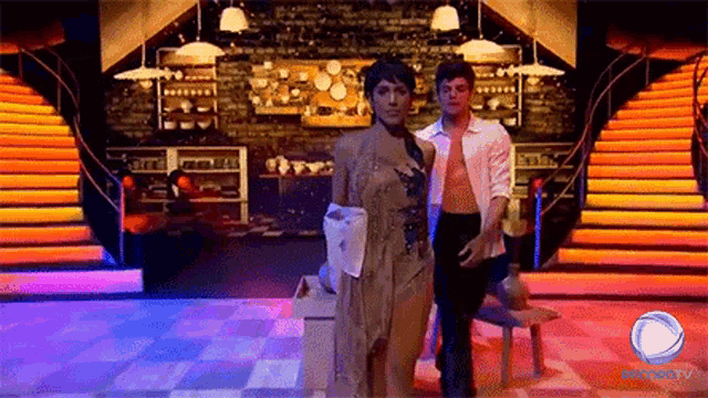 a man and a woman are dancing on a stage with stairs behind them .